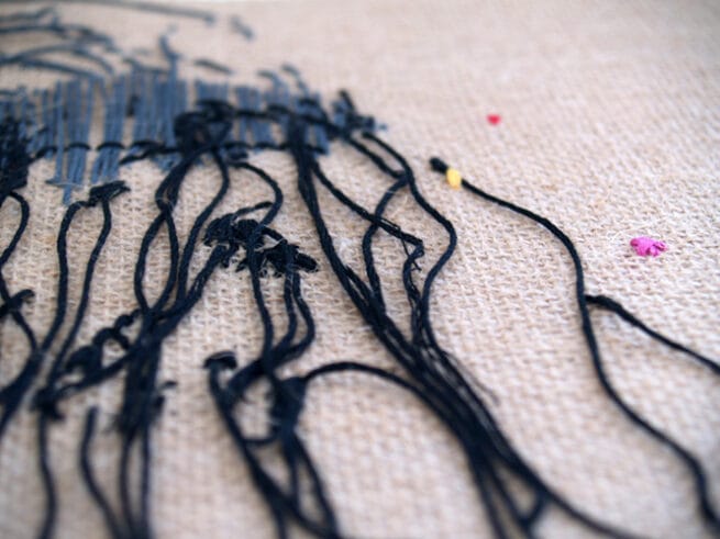 Fuegos III. detalle en perspectiva de los hilos bordados a mano sobre tela de arpillera